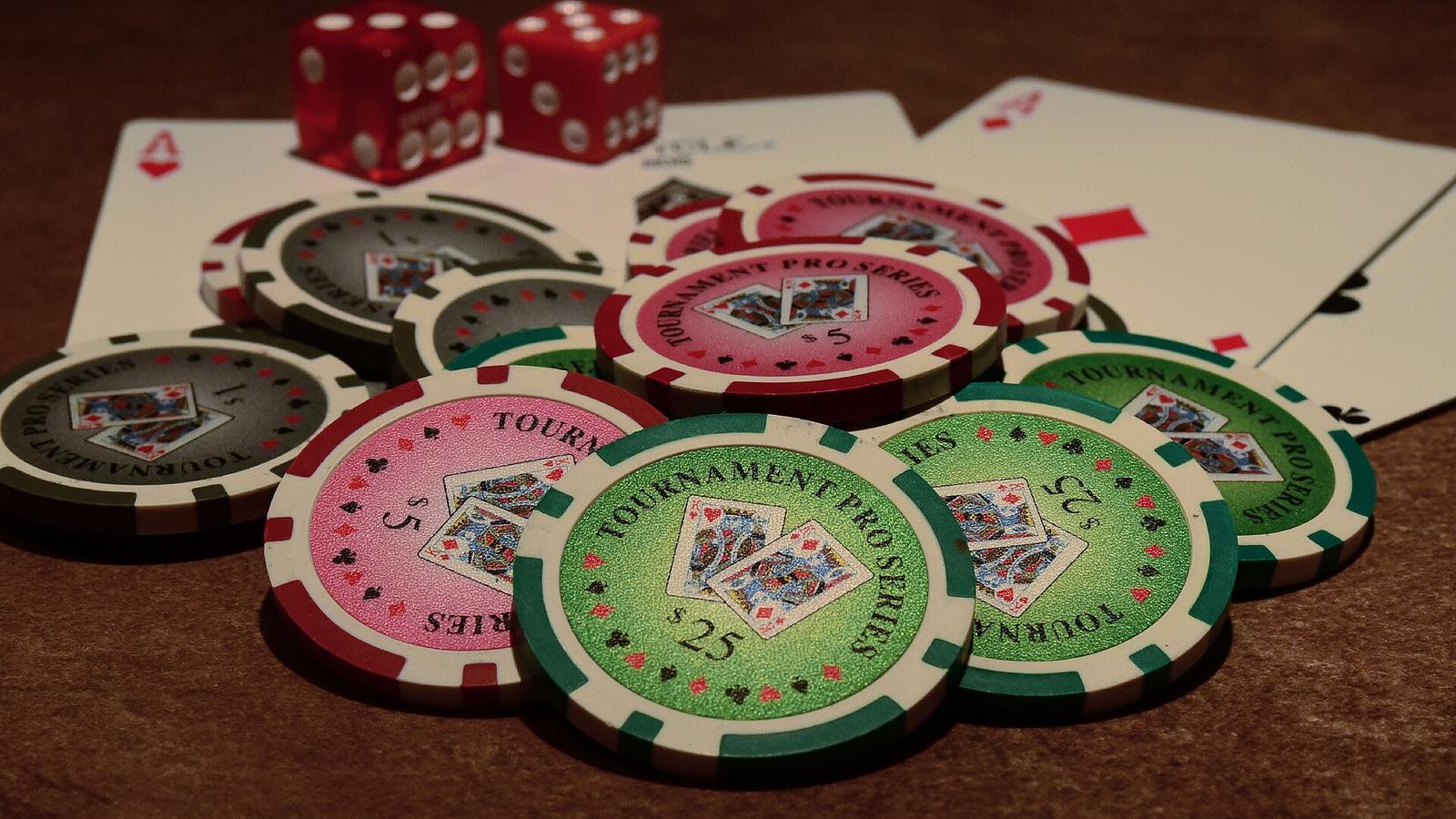 Poker chips with playing cards and red dice on a table